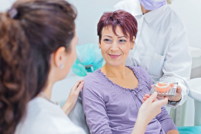 Dental implant surgeon showing dentures to a patient